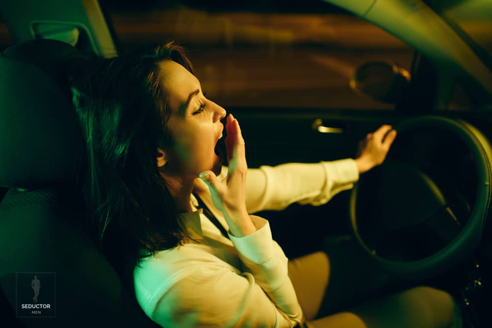 Mujer agotada bostezando en su carro